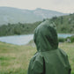 A person in a MellowConceptStore Waterproof Baby/Kid Clothing Set in Khaki gazes out at a mountainous landscape with a lake in the distance.