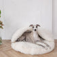 A greyhound dog lounging in a Mellow Pet Store Natural Sheepskin Pet Cave - White.