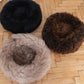 Three Round Natural Sheepskin Pet Beds - Brown from Mellow Pet Store on a wooden floor.