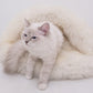A white cat lounging on a fluffy Natural Sheepskin Pet Cave - White bed from Mellow Pet Store.