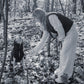 A woman is petting a Woolen Dog Vest - Charcoal by Mellow Pet Store in the woods.