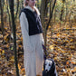 A woman standing next to a Woolen Dog Vest - Charcoal from Mellow Pet Store in the eco-friendly woods.