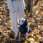 A woman standing in the woods with her Mellow Pet Store Woolen Dog Vest in Charcoal on her greyhound dog.