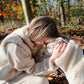 A woman is petting a Woolen Dog Vest - White in the woods from Mellow Pet Store.