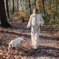 A woman, dressed as a Jedi, strolling with her dog in the woods wearing a White Woolen Dog Vest from Mellow Pet Store.