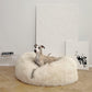 A dog relaxing on a Mellow Pet Store Oval Natural Sheepskin Pet Bed.