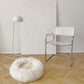 A Round Natural Sheepskin Pet Bed from Mellow Pet Store is resting on a wooden floor.