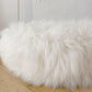 A Round Natural Sheepskin Pet Bed from Mellow Pet Store on a wooden floor, made of natural sheepskin.
